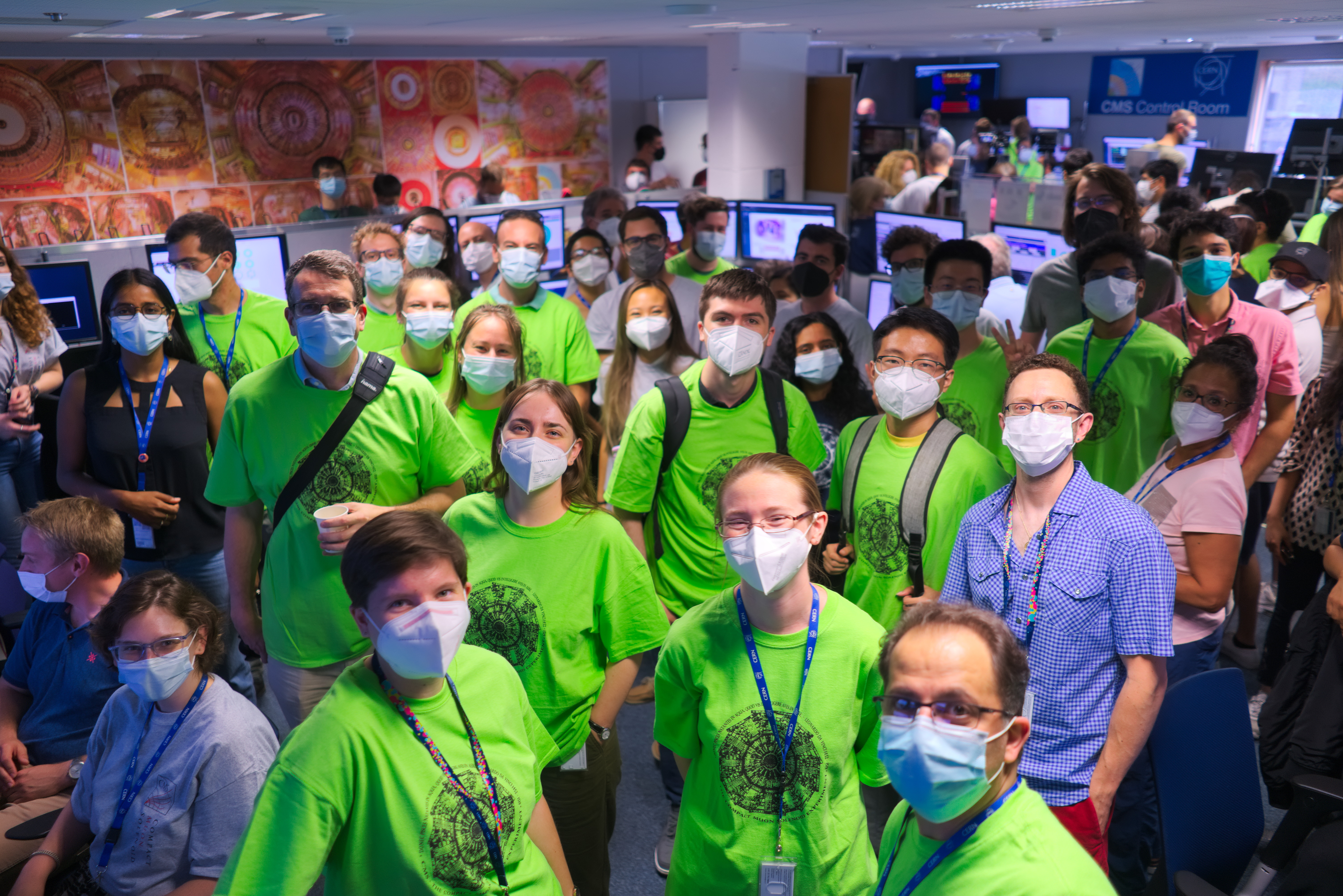 Das Bild zeigt eine Gruppe von Physiker*innen in grünen T-Shirts im CMS Kontrollraum nach den ersten Kollissionen mit 13,6 TeV