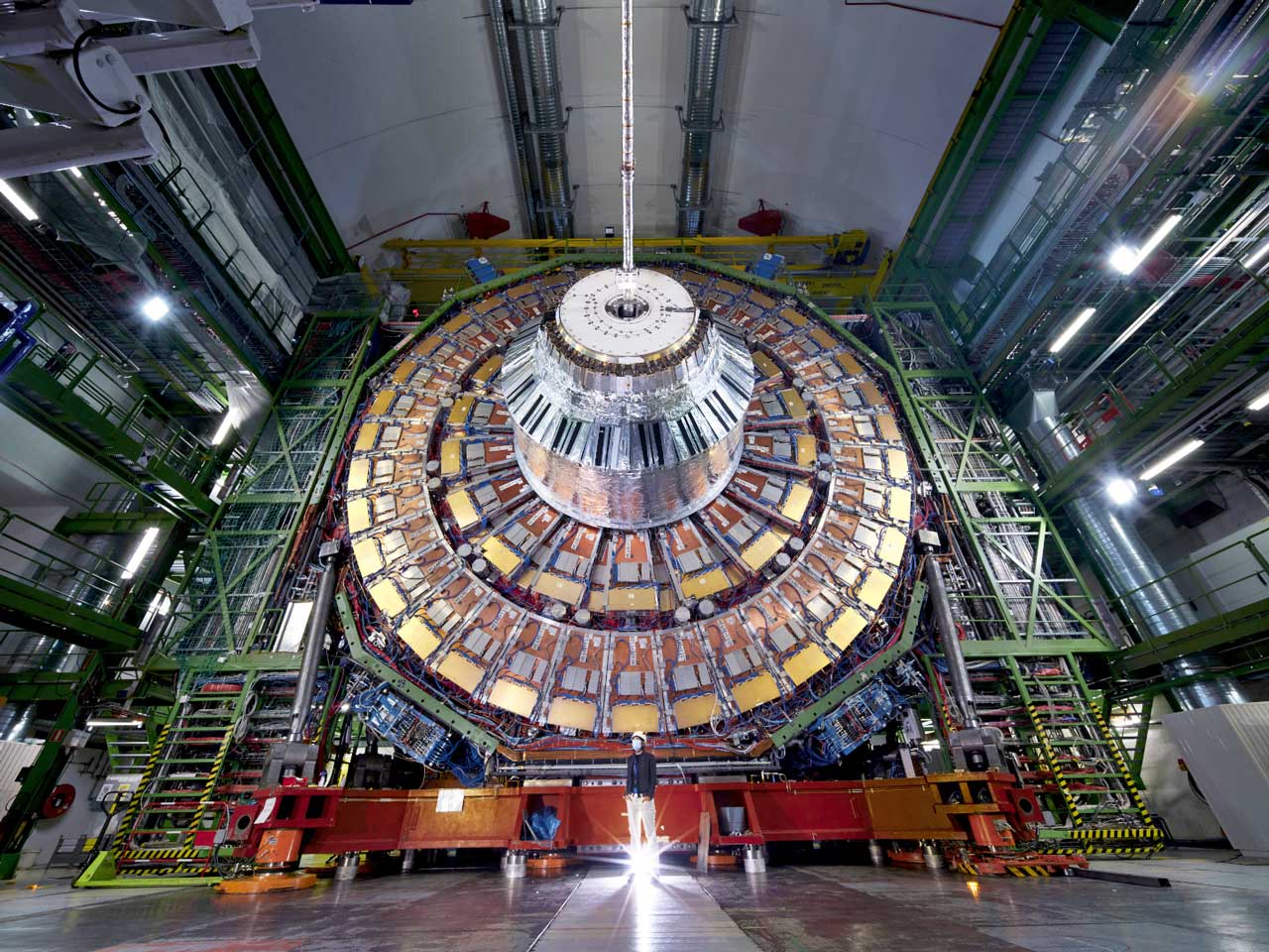 An employee stands in front of the open CMS particle detector.